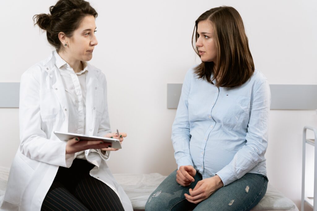 Eine schwangere Frau, die sich mit einer Ärztin in einer medizinischen Klinik berät.